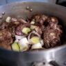 Oxtail and beef bones cooking in a pot with vegetables, showing slow cooking method for flavorful meals