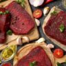Raw grass-fed beef steaks with herbs and ingredients on a wooden surface for meal preparation