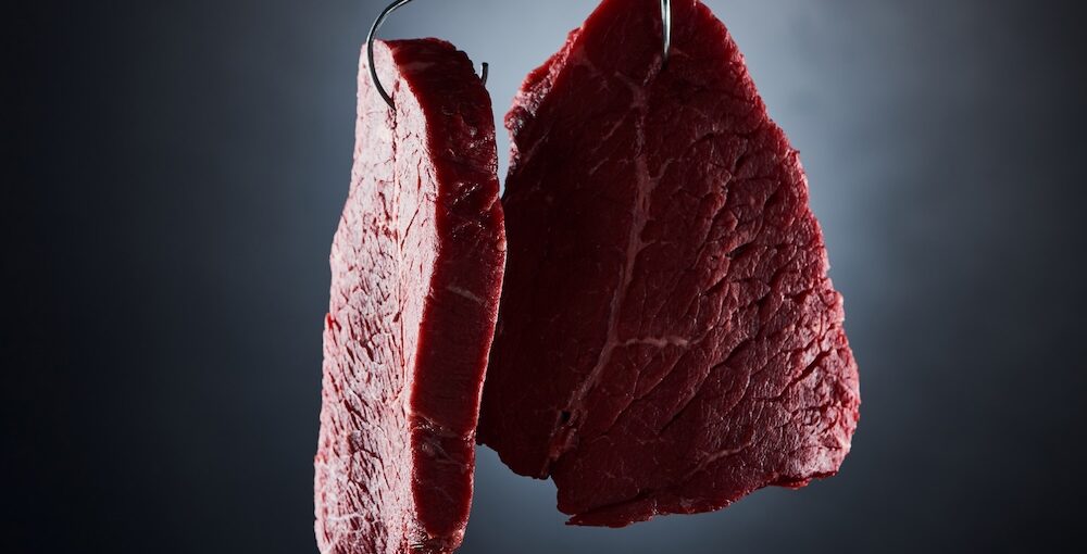 Raw grass-fed beef steak being prepared and dried before cooking to ensure proper thawing and searing