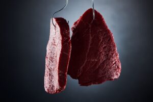 Raw grass-fed beef steak being prepared and dried before cooking to ensure proper thawing and searing